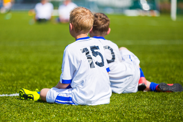 Youth Soccer players sitting on soccer field at youth soccer tournament