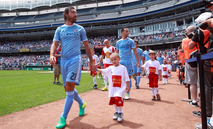 MLS Soccer News - New York City FC midfielder Andrea Pirlo (21) walks a young fan to the pitch before a game against the New York Red Bulls Credit- Brad Penner-USA TODAY Sports